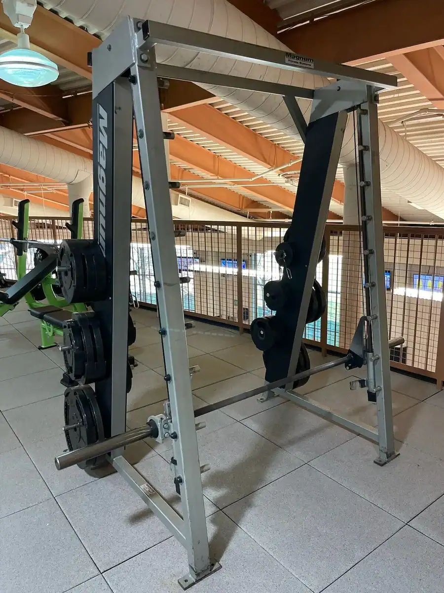 Barbell power rack with weight plates at Colorado Cardio gym, high-quality fitness equipment for strength training and muscle building, modern health club setting in Denver, Colorado.